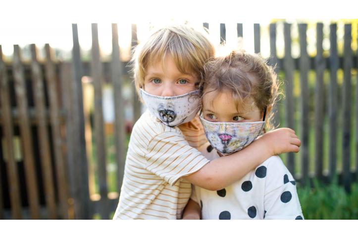 Two toddlers hugging while wearing facemasks