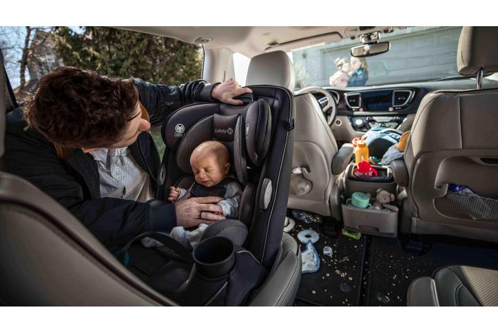 infant being buckled into a convertible car seat